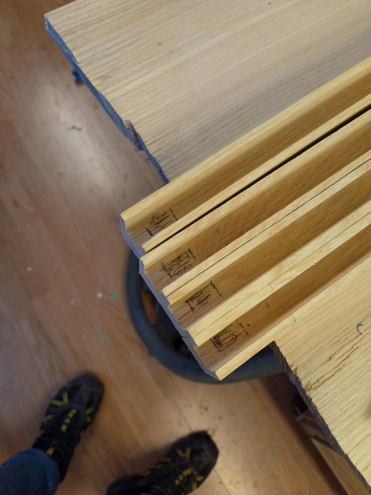 Trädelar med markerade tappar redo för montering i verkstadsinställning.