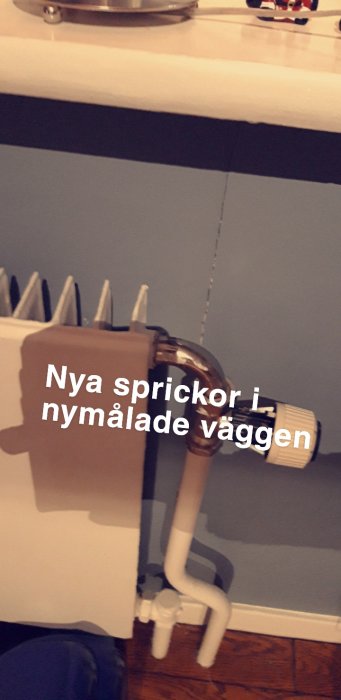 Nymålad vägg med synlig spricka vid ett rör och radiator, text "Nya sprickor i nymålade väggen".