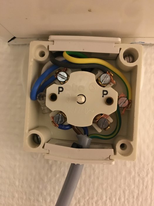 Öppen eldosa med elektriska kablar och en omkopplad blå kabel istället för en vit i vägginstallation.