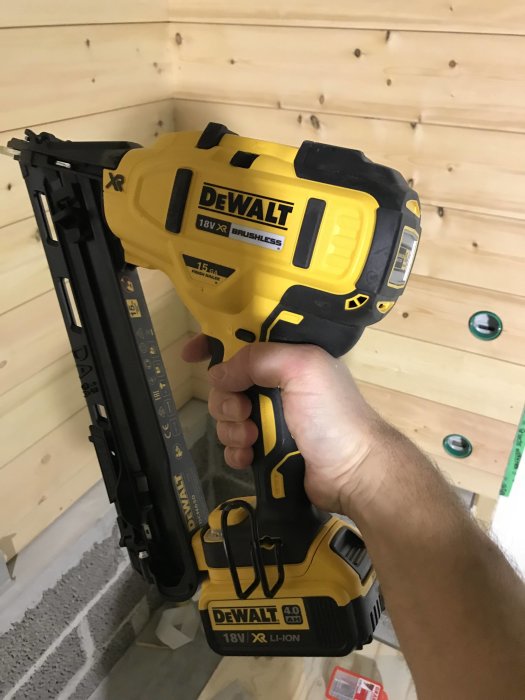 En hand håller ett gult och svart Dewalt 18V spikpistol utan dyckert.