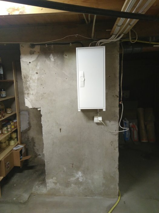 Nytt, monterat elektriskt skåp på en ojämn betongvägg med synliga kablar och tomma röröppningar upptill.