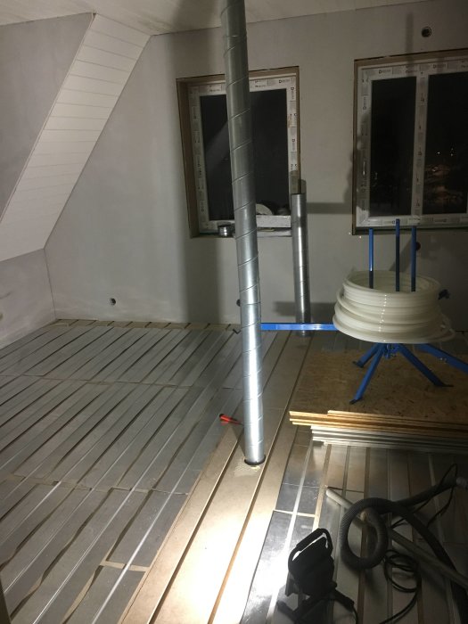 Nyinstallerad golvvärme och påbörjad ventilation med rör i ett utbyggnadsprojekt.