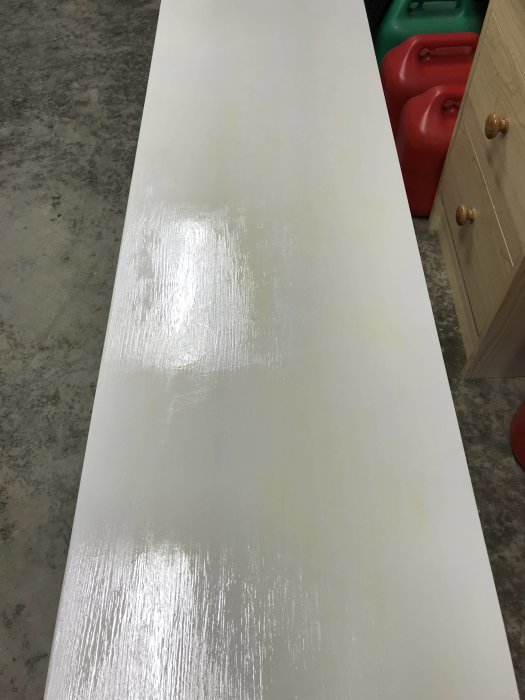 Platsbyggd sittbänk målad i antikvit med synliga gulflammor från gammal golvlack.