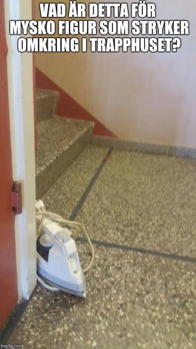 Ett strykjärn står parkerat vid en dörröppning i ett trapphus med röda väggar och stenmosaikgolv.