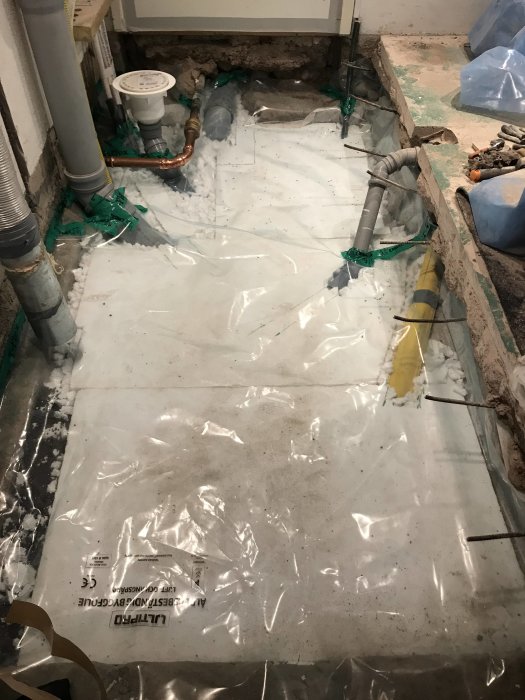 Källarrenovering med nylagt plastskikt ovanpå cellplastisolering och radonslang i makadam.