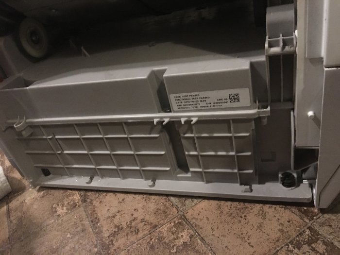 Interiör av kylskåp med kondensatorn synlig, inbyggd bakom plastpanel.