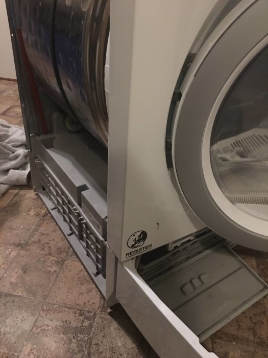 Torktumlare med öppen bottenplatta som visar kondensator och inbyggda delar.