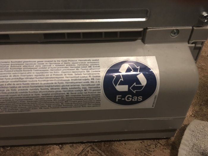 Förslutet utrustningsskåp med F-gas- och återvinningsdekalerna synliga.