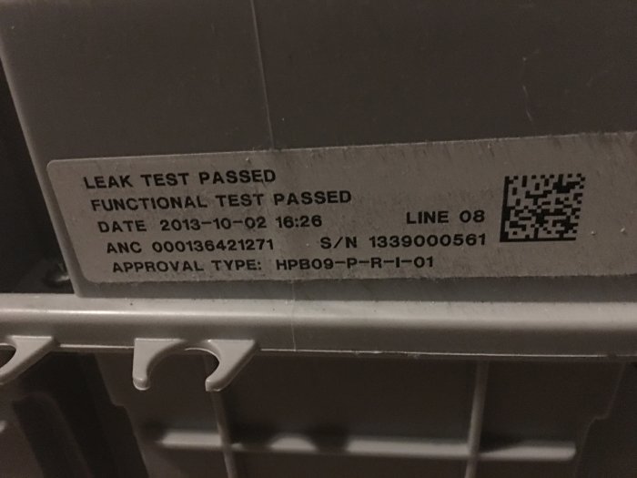Klistermärke på utrustning med texten "LEAK TEST PASSED" och QR-kod, indikerar en godkänd läckagetest.