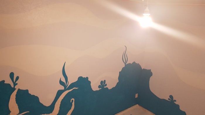 Renoverat rum med ombre väggmålning i blå och beige toner med abstrakta blomstermönster.