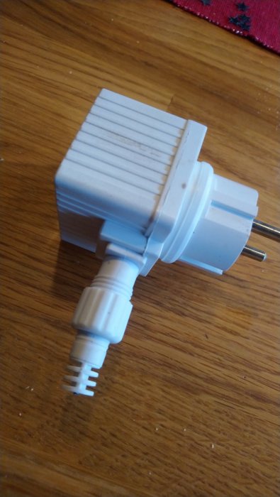 Avbruten elkabel vid kontakten på ett träbord, kan behöva repareras.