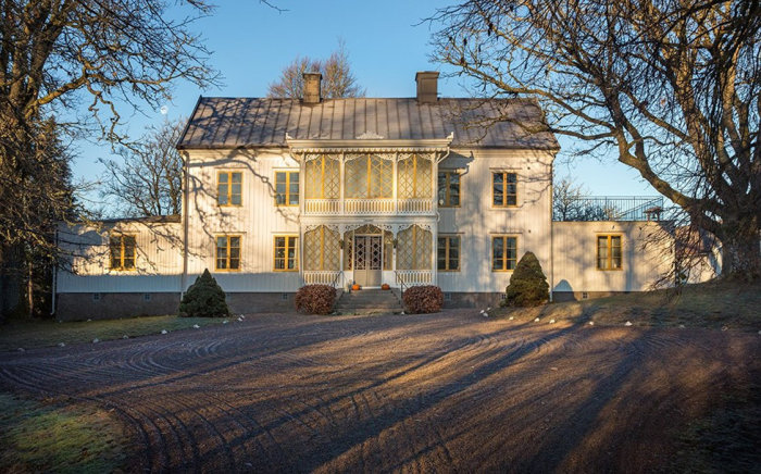 1800-talshus "Norra Kyrkeby" med veranda i Visselfärda, grusuppfart och omgivande träd.