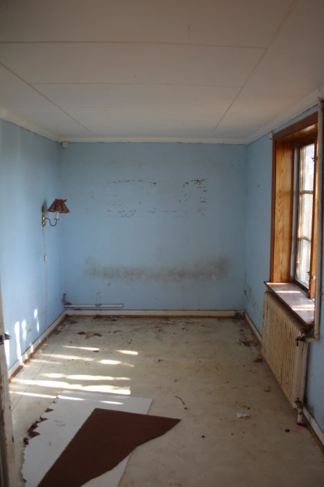 Renoveringsprojekt: Tomt rum med blå väggar och slitna ytor i behov av renovering.