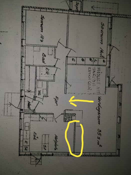 Arkitektritning av ett hus med markerad vägg mellan matplats och vardagsrum samt en pil vid skorstenen.