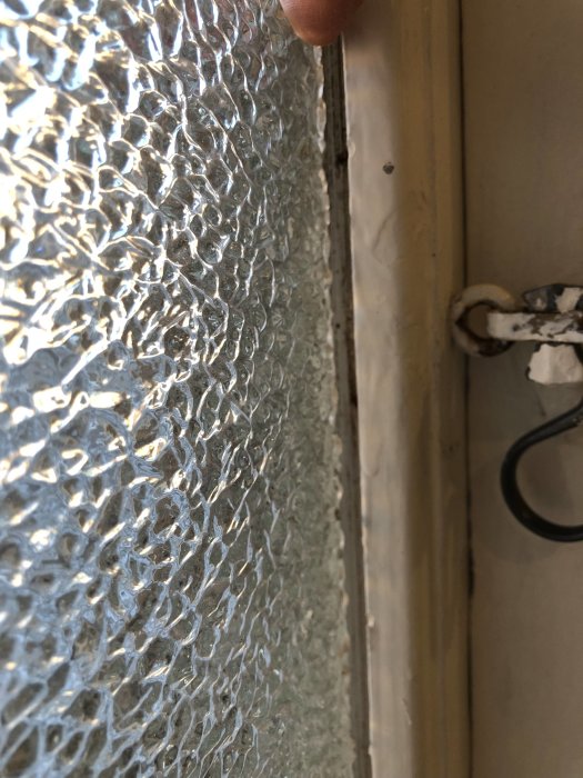 Närbild på plastfönster med bubblig textur som är löst fäst med spikar och visar tecken på drag.