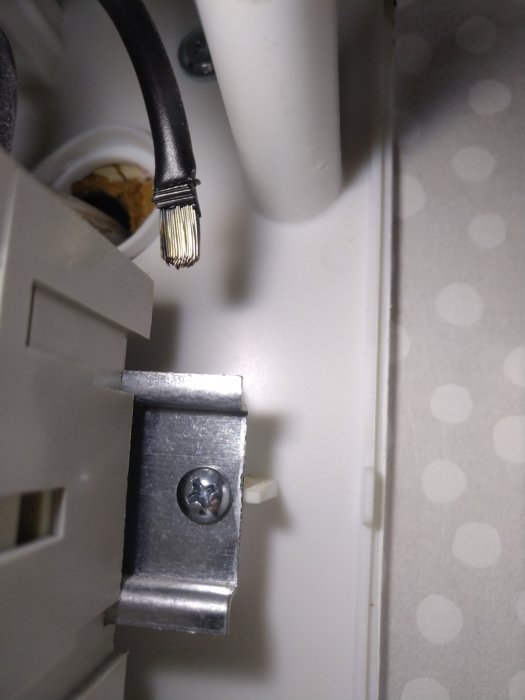 Elkabel med blottade ledare nära en skarvklämma i en apparatlåda.
