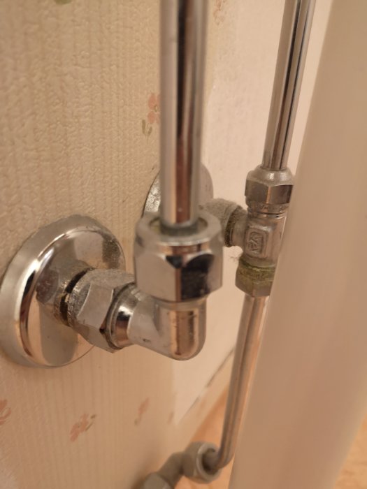 VVS-installation med rör och kopplingar som förgrenar sig uppåt och nedåt mot väggen.