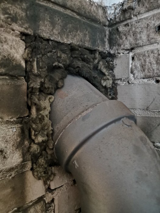Kaminrör insatt i murstocken med synlig isolering runt om, indikerar en äldre metod för att täta röranslutningen.