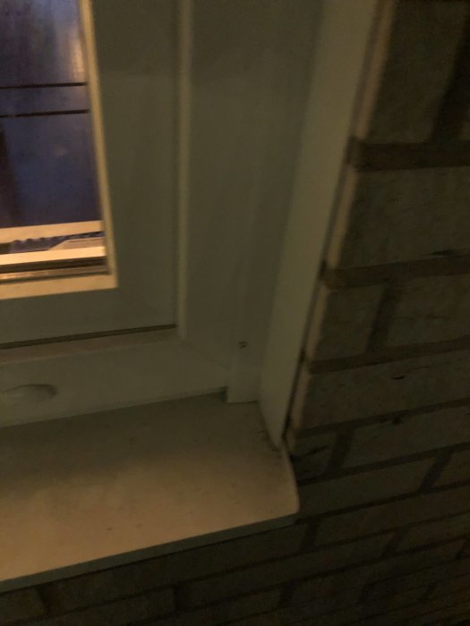 Färdigmonterade vita plåtar runt fönster med tegelvägg i skymningen.