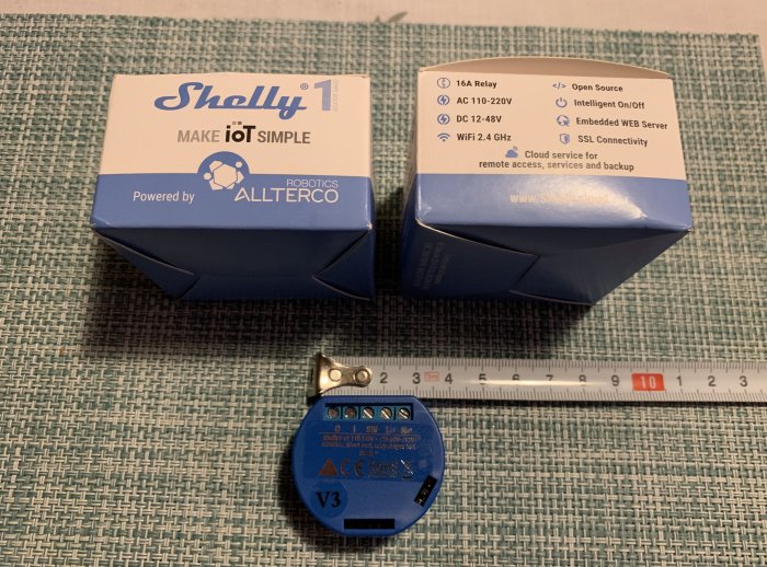 Shelly 1 smarta reläer med förpackningar och ett måttband som visar storlek.