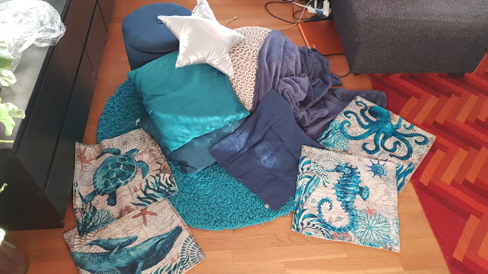 Mys-hörna med marina temakuddar föreställande bläckfiskar och maneter på en färgglad matta med kuddar och filtar.