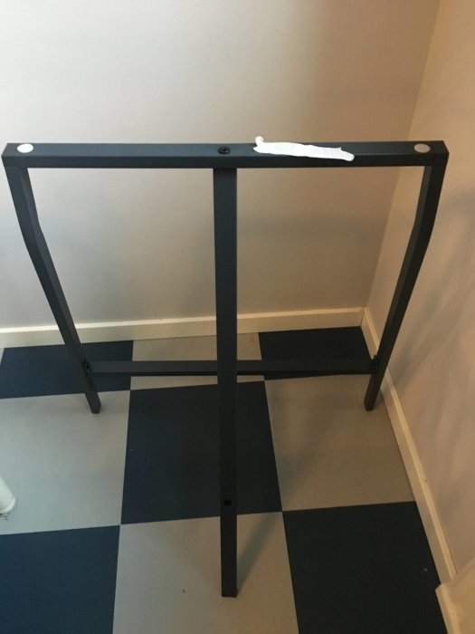 Svart IKEA LERBERG benbock står på ett blått och vitt rutigt golv mot en ljus vägg.
