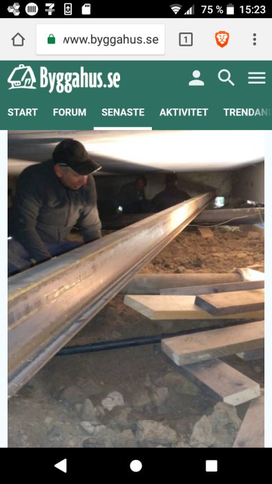 Person som arbetar med att installera en balk på plintar under ett hus för att stabilisera golvet.
