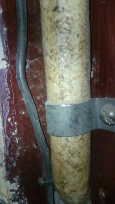 En äldre blymantlad kabel och en pappisolerad GEBE/EDIL-kabel fastsatta på en vägg, möjlig telefonkabel.