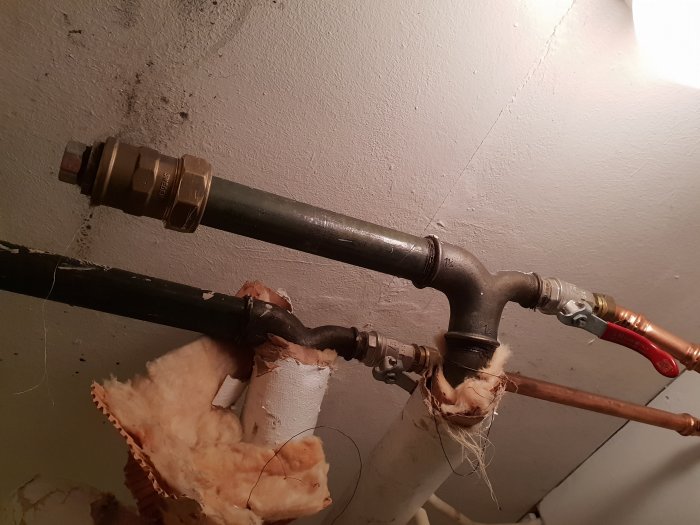 Ett gammalt rör med isolation och en ny koppling som ersatt den defekta delen.