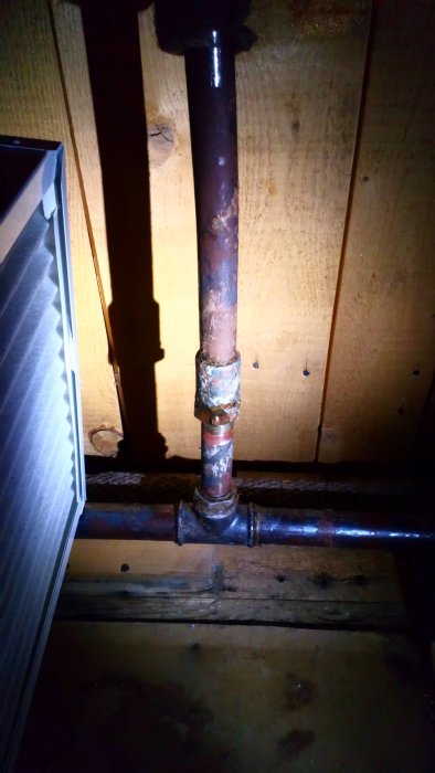 Radiatorrör med en synlig läcka vid en skarvkoppling mot en vägg i ett äldre hus.