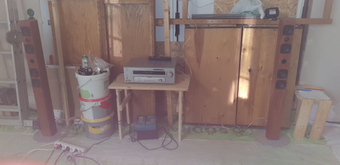Begagnat stereo-system med två högtalare och en förstärkare placerade i ett pågående byggprojekt.
