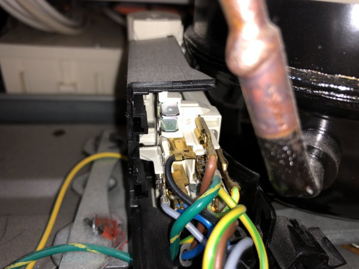 Närbild av kompressoranslutningar och startautomatik med synliga terminaler och ledningar.