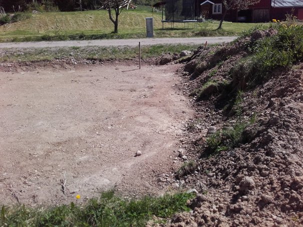 Grävd och jämnad yta för grund med synliga grushögar och jordvallar på en byggplats.