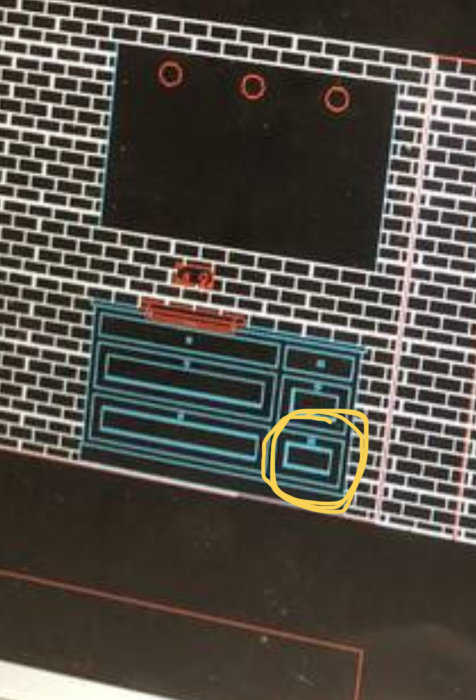 Verktygslåda i blå och svart med markerad detalj, framför tegelvägg och bänkskiva.