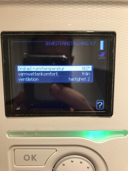 Digital termostat med meny för semesterinställning och inställningar för rumstemperatur och ventilation.