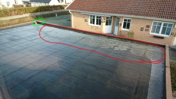 Platt garagetak med stående vatten och skadad takpapp, behov av renovering.