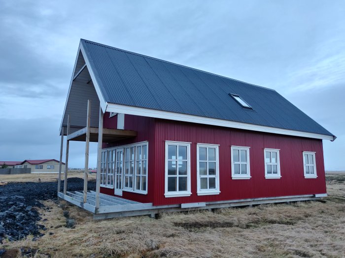 Nybyggt rött hus med två våningar på Island, takfönster och farstukvist.