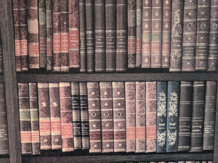 Tapet som liknar en bokhylla med gamla böcker, monterad upp och ner på en vägg.