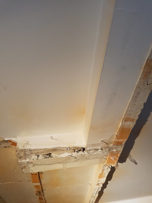 Ventilationssystem i taket med synlig plast och skadat område där tegel och möjligen asbestmaterial syns.