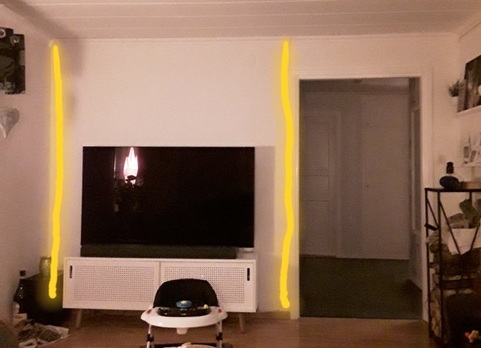 Vägg med tv och markeringar där en person planerar att installera LED-slingor mellan vågrätta paneler.