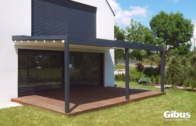 Aluminiumpergola i storlek 4x7 meter vid en modern vit husfasad med gräsmatta omkring.