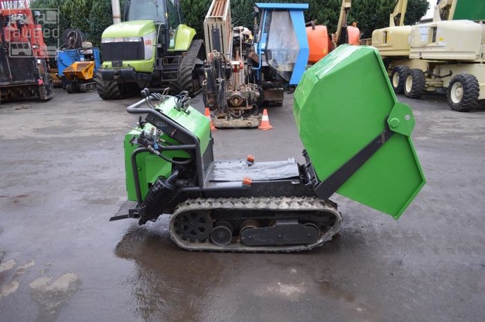 Grön minidumper med band på en grusplan, används för källargrävning och materialtransport.