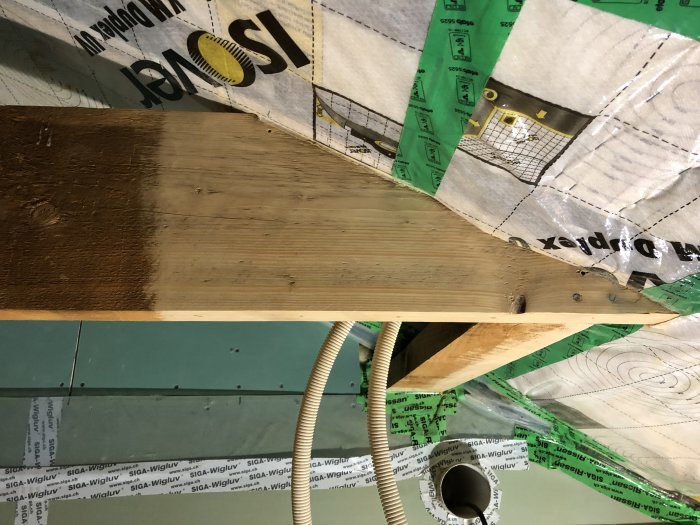 Halvslipat trägolv med mörk fläck intill oslipad del, sliputrustning synlig, under renovering.