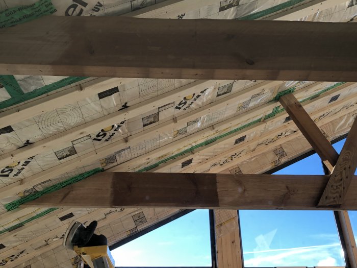 Takbjälkar i trä och isoleringsmaterial under byggnadsrenovering.