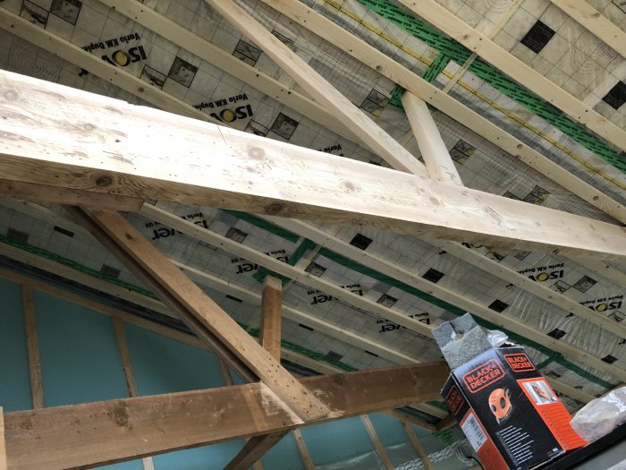 Ny slipad takstol med synlig isolering och en slipmaskin från Black & Decker i ett pågående renoveringsprojekt.