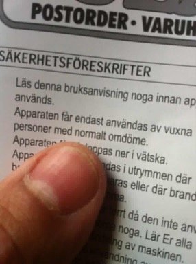 Närbild på en hand som pekar på en säkerhetsföreskrift i en bruksanvisning.