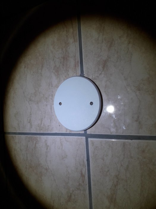 Ett vitt rundat täcklock för kablar på en kakelvägg, installerat där takfläktens sladdar tidigare var synliga.
