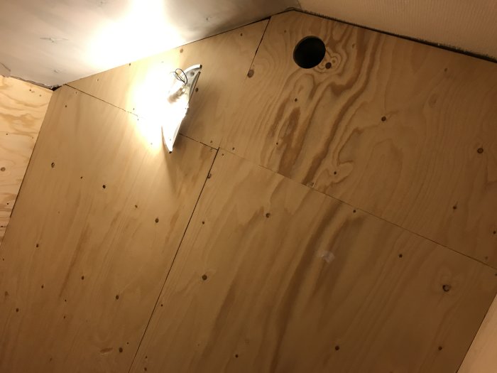 15mm plywood monterad på innertak med synliga skruvar och utskärningar för armaturer.