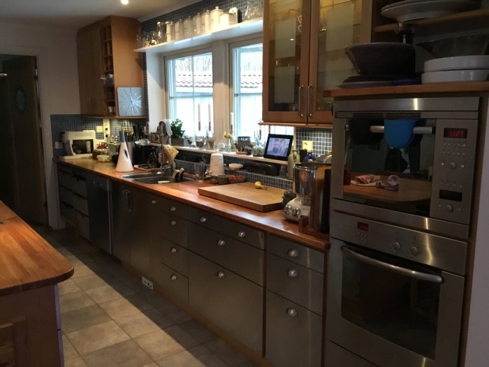Uppgraderat kök med nya rostfria luckor och lådfronter, trädgolv och träbänkskivor, moderna apparater.