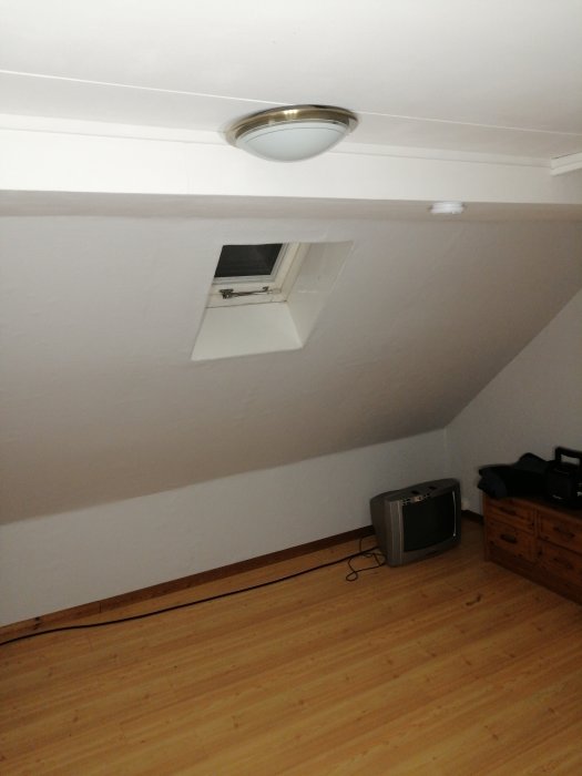 Välupplyst vindsrum med takstrålkastare, trägolv, TV och takfönster.